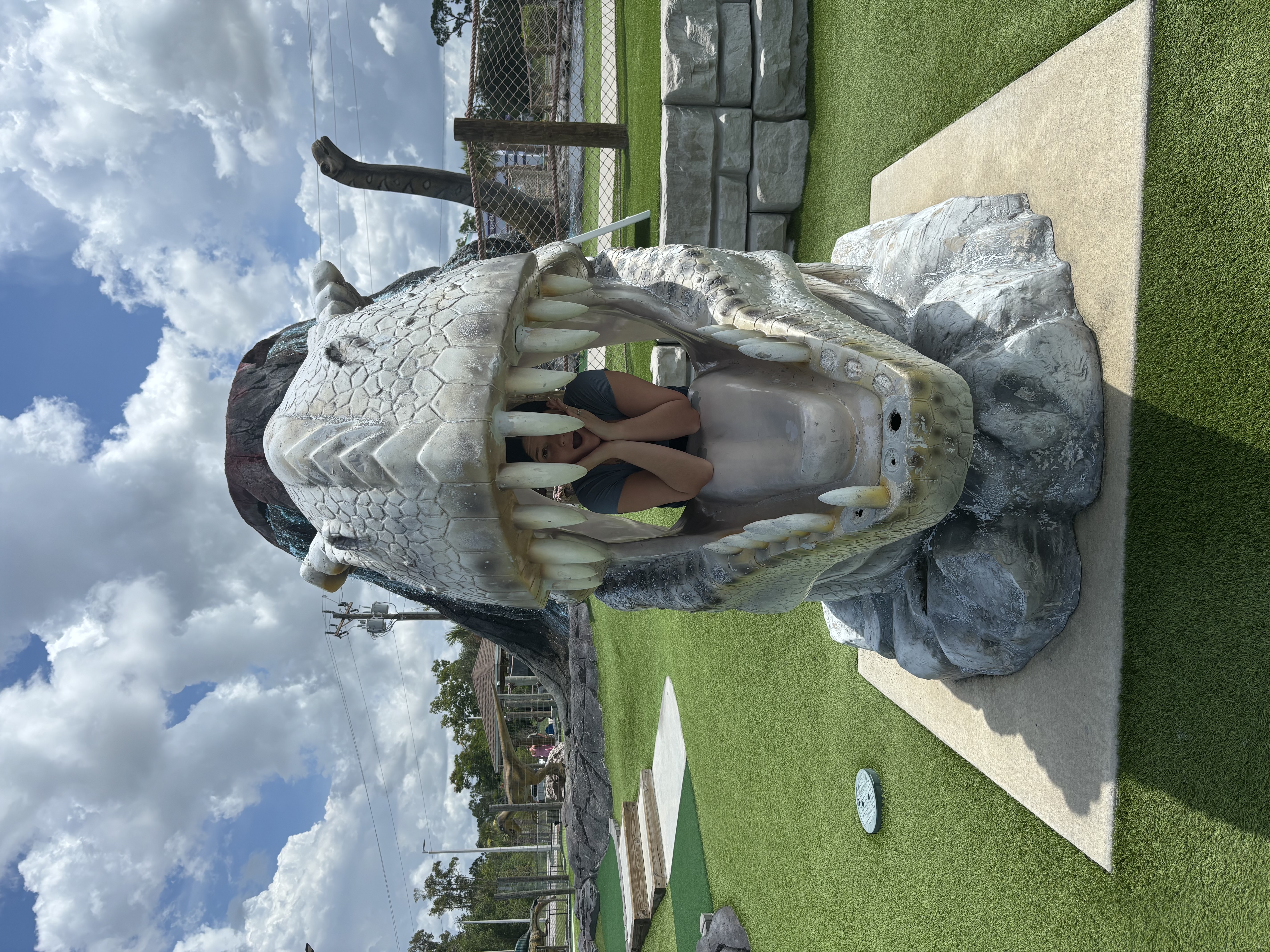 My wife posing inside the open mouth of a large dinosaur sculpture