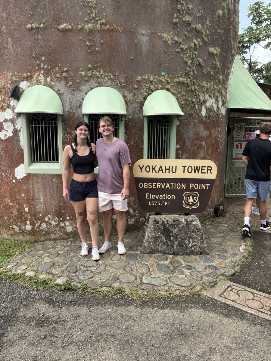 My wife and me standing beside the Yokahu Tower observation point sign in Puerto Rico